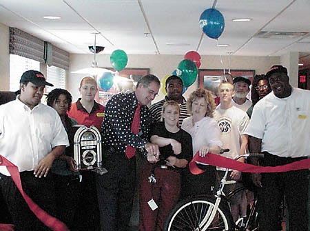City Commissioner Dave Dershimer helps DennyÕs General Manager Cindy Larramore cut the ribbon as customers and employees look on at the dinerÕs grand opening Sunday. DennyÕs relocated to Cypress Gardens Boulevard in April after the Department of Transportation bought out their Third Street location for the widening of U.S. Highway 17.
