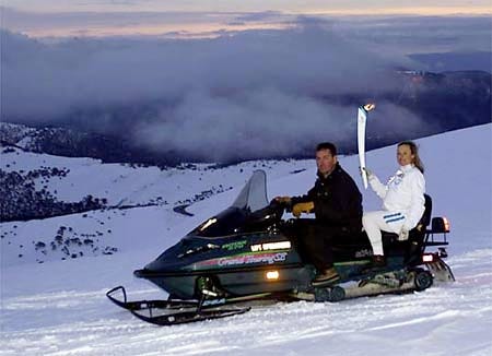 Torchbearer Jenny Altermatt carries the flame aboard a snowmobile on the summit of Mt. Hotham, Australia.