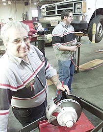 Bob Furtado, automotive technology teacher at Cape Cod Regional Technical High School in Harwich, believes hands-on testing equipment, such as the disc brake rotor he?s holding, is more suitable for vocational school students than the current MCAS exams.