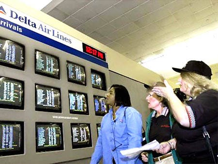 Dee Williams, left, Diane Robertson, center, and Janice Dolan, react as they see on a Delta Air Lines arrival board at Hartsfield Atlanta International Airport that the flight they were meeting passengers from, Delta Flight 1069 from Boston, had been canceled Monday. Delta canceled more flights Monday because pilots refused to work overtime as contract talks continued between their union and the carrier.
