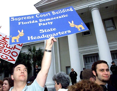 Ron Stone of Tallahassee, holds up a sign in front of the Florida Supreme Court Friday. A court spokesman had just read a ruling by the high court that said Florida counties could recount the undervote ballots.