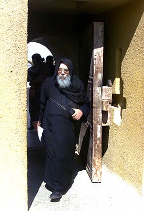 Father Yohanna, who came to the 4th century monastry of St. Macarius in 1969, the same year as the current abbot Father Matha, enters the monastery's ancient gate as he carries a Japanese-made cordless telephone, Feb. 18. Thirty-two years after their arrival, the once-derelict retreat in the desert about 65 miles west of Cairo runs an agribusiness and communicates with the outside world via fax and the Internet.