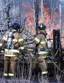 Yarmouth firefighters try to contain a fire started in Meadowbrook Conservation area near Swan Pond yesterday by boys playing with cigarette lighters.