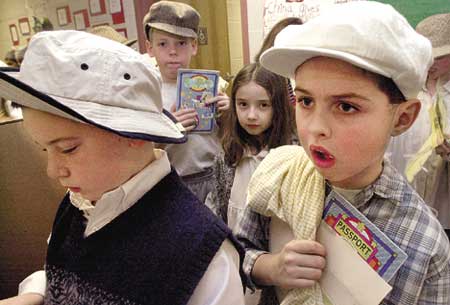Tim Hunter,8,(left) and Albie Pace.8(right) wait in line with their passports ready to board a ship to Ellis Island during a program at the Stratham Memorial School on Thursday morning.