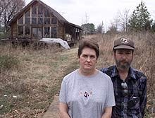 Tom and Lynn Milam stand in front of their unfinished dream home in Hernando, Mississippi. The couple claim to have been poisoned by using arsenic treated wood.