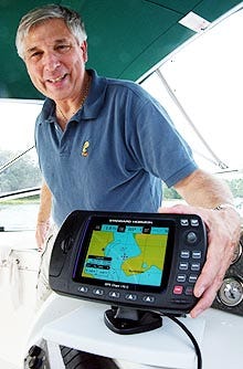 Bob Sweet of Cotuit stands with his GPS system on his boat moored near his home.
