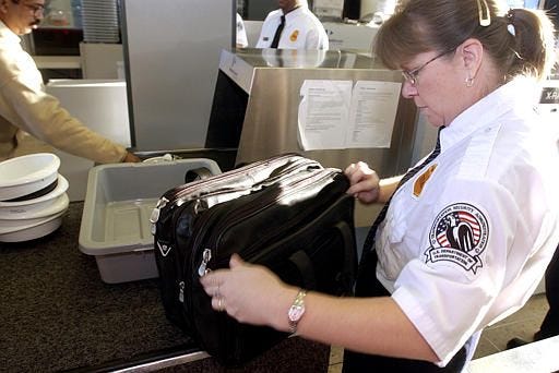 Carey Ann Bianchi of the Transportation Security Administration looks trough a bag at a security checkpoint at Chicago's O'Hare International Airport on Tuesday. The government takeover of security at the nation's airports was complete Tuesday.