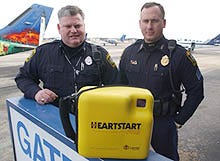 Barnstable police Officer Kevin J. Donovan, left, and Sgt. Ben Baxter with a portable defibrillator at Barnstable Municipal Airport in Hyannis. The machines, used to help heart attack victims, are becoming increasingly common around the Cape and can be found at schools, beaches, golf courses, ferries, health clinics and the airport as well as in police cruisers.