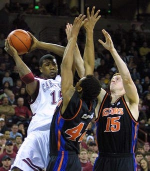 South Carolina's Carlos Powell, left, looks for a teammate as he is defended by Florida's Matt Bonner (15) and Bonell Colas on Saturday night in Columbia. The Gators prevailed 77-75.