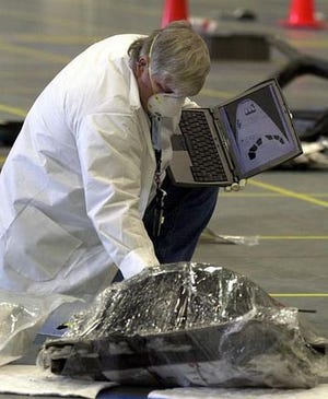 A member of the Columbia investigating team holds a computer with the foward section of a shuttle displayed as he checks through Columbia wreckage in a hangar at the Kennedy Space Center in Cape Canaveral, Fla. Friday Feb. 14, 2003.