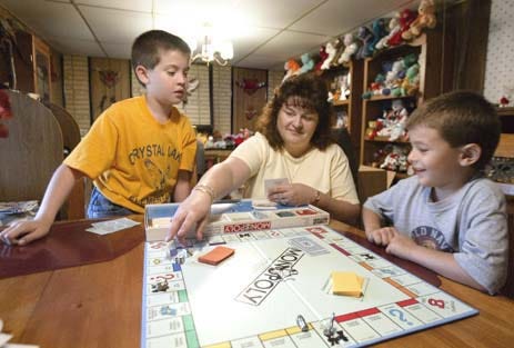 From left to right, Brandon Pach, 10, his mother Shawnette Drury and Austin Drury, 5, play a board game at their home in the Skyview area in East Lakeland on Thursday.