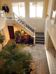 The main room of the underground Ecology House once looked out onto a garden courtyard, (photo below) that the Varjian family turned into a subterra-nean atrium, (photo above) as the centerpiece of their three-level home.