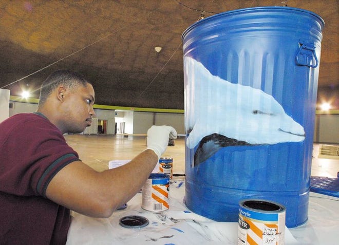 Winter Haven engineering technician Berlin Cassamajor paints a dolphin on the side of a trash can in Winter Haven on Tuesday. City workers are painting the cans for a silent auction to raise money for the American Cancer Society's Relay for Life. Below, a stylized cat is one of several cats painted on a can by Human Resources Director Julia McKnight.
