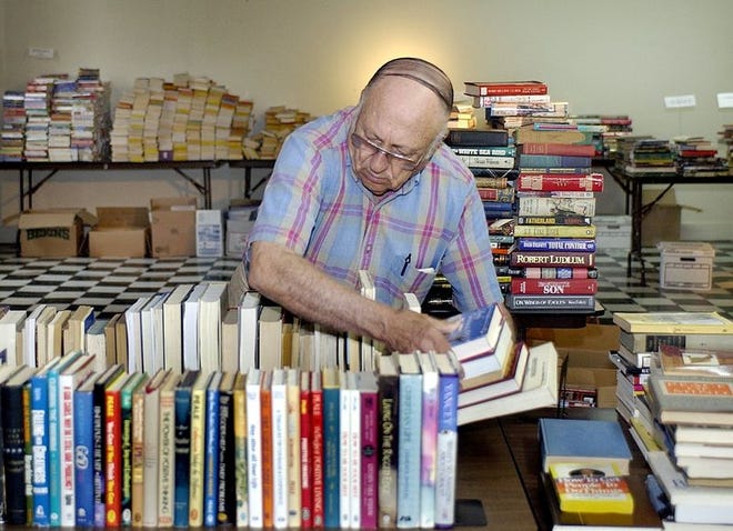 The Rev. Morris Hollifield arranges books on religion at the old White Star building on Main Street Monday morning as the Friends of the Lexington Library prepares for its third annual book sale Friday through Sunday.
