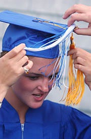 Maura Sweeney of Falmouth, one of 23 students to graduate from Falmouth Academy yesterday, gets some help straightening her mortarboard and tassel before the ceremony.