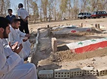 Friends and family members recite parts of the Koran over the graves of Saddam Hussein's sons, Odai and Qusai, and Qusai's son, Mustafa Hussein, 14, yesterday in Tikrit, 110 miles north of Baghdad. The bodies of Saddam's sons were wrapped in Iraq flags as a sign the family considered them martyrs.