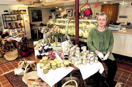 Nancy Briggs Guilmette slices brie at C?est Cheese in North Hampton where she offers a selection of domestic and international cheese.