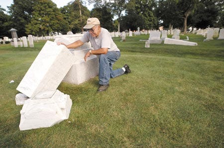 George Dufoour, maintenance supervisor at the Linden Street cemetery in Exeter, inspects damge to one of the 40 headstones that were vandalized over the weekend.