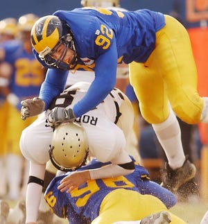 After releasing a pass, Wofford quarterback Trey Rodgers is smashed by Delaware's Chris Mooney (92) and Shawn Johnson.