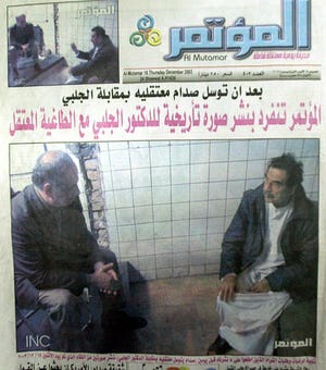 This front page of Al-Moutamar newspaper published in Baghdad on Thursday shows a picture of Saddam Hussein, shaven and in captivity, sitting on the floor across from Ahmed Chalabi, a member of Iraq's American-picked Governing Council. The picture was taken Sunday when Chalabi and three other council members were taken to see the former dictator. Headline reads: After Saddam begged Americans to meet Chalabi, Al-Mutamar exclusively releases the historical photograph for Dr. Chalabi with the arrested dictator.