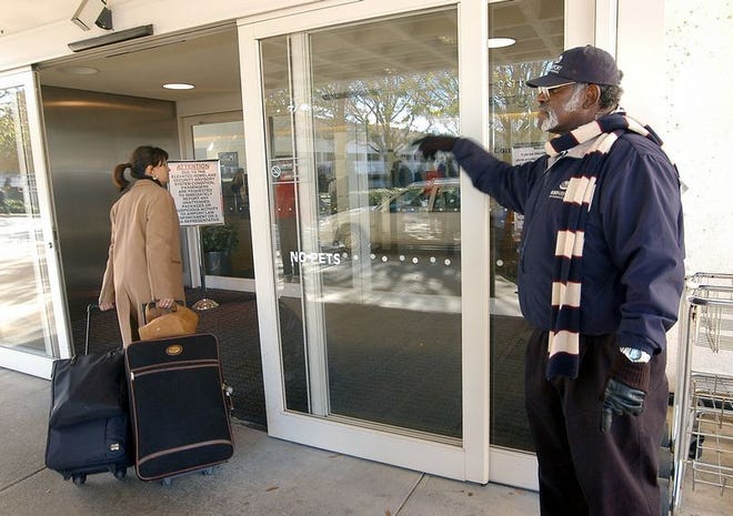 Reid Sullivan greets passengers and helps with baggage Friday morning at GSP International Airport. Sullivan says he usually carries 30 to 40 bags a day and estimated he's carrying 65 percent more luggage during the holidays.