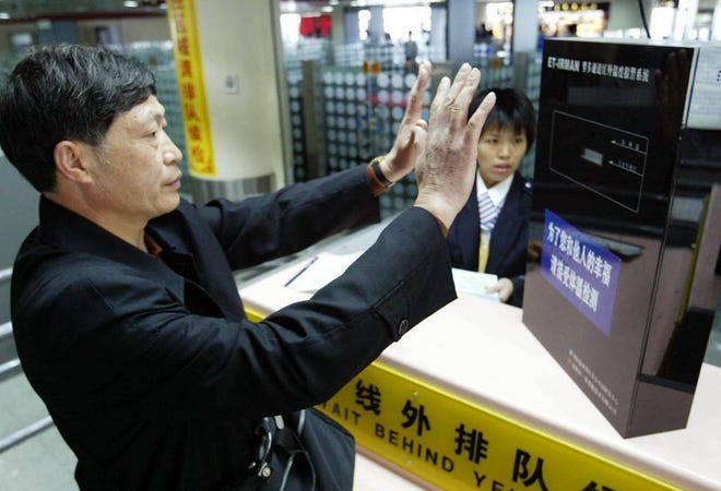 A Chinese man places his hands before an infrared
temperature monitor at the Meilan airport in Haikou, southern China. The recent confirmed case of SARS in Guangzhou has raised awareness for such checks ahead of the peak season of
passenger travel during the Spring Festival.