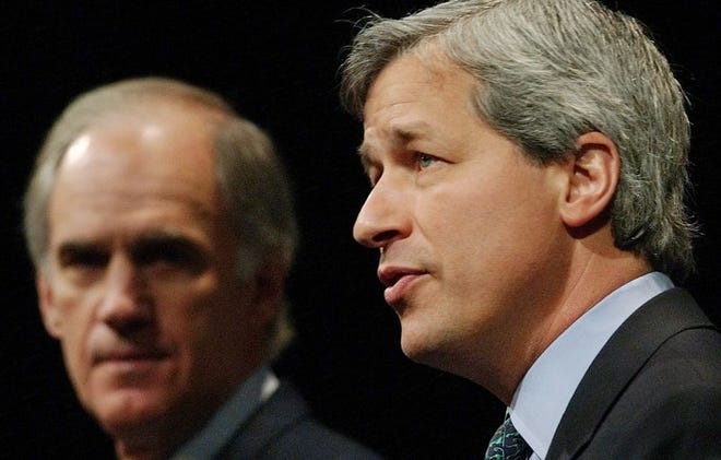 Bank One CEO Jamie Dimon addresses analysts Thursday in New York as William B. Harrison Jr., left, CEO of J.P. Morgan Chase, listens.