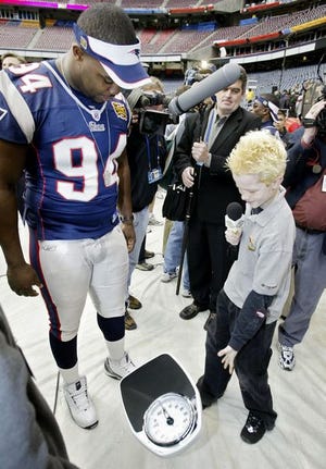 Justin Phillips, 13, working
for Nickelodeon's Games and Sports for Kids, asks New
England Patriot Ty Warren to prove he weighs 297 pounds Tuesday, at Reliant Stadium in Houston.