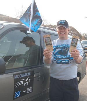 Kenny Church shows off a pair of Super Bowl tickets before leaving Friday for the big game. Church is taking a banner that was signed by Carolina Panthers fans at The Beacon.