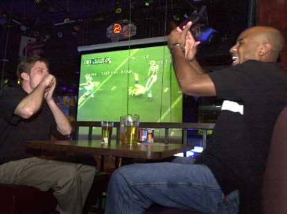 Jody Crenshaw, left, and friend Jermaine Jeffrey react to a play during the Super Bowl at JP Gators at SW 13th Street on Sunday. Although Crenshaw and Jeffrey are watching the game together, they are rooting for different teams. "I just despise New England, so I have to hope that Carolina wins," Jeffrey said.