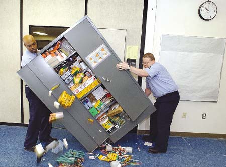 USS Norfolk crew members Corwin Lester, left, and David Blount are slowed up for a moment when a cabinet filled with school supplies they were moving at the Mitchell School in Kittery Point, Maine, began to spill its contents.