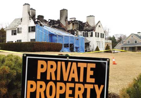 The remains of a summer home owned by Milton Peterson, of Virginia, is surrounded by police tape after a four-alarm blaze severly damaged the residence at 15 Milbury Lane in York on Wednesday.