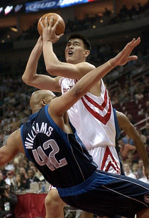 Dallas' Scott Williams hits the floor as Yao Ming shoots in Houston.