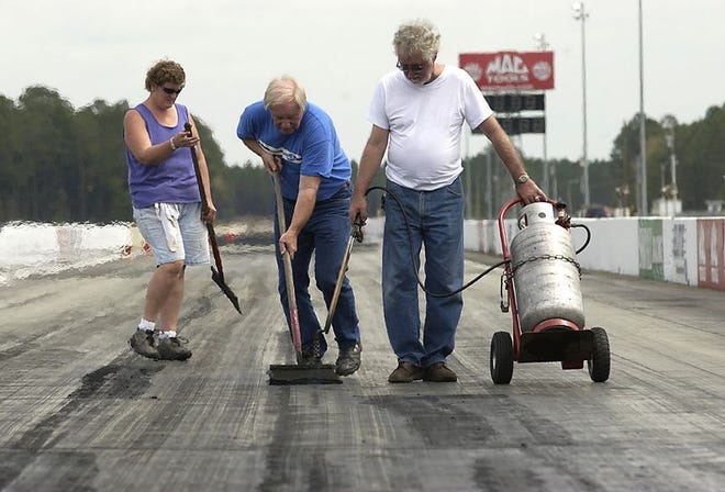 NHRA Safety Safari crew members, from left, Robin Crosby, Louie Murray and Richard Cooke remove old rubber from a 330-foot section of the quarter-mile track at Gainesville Raceway on Monday. Work crews are gearing up for Gatornationals, which starts Thursday.