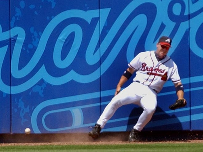 Chipper Jones grabs his right leg and collapses against the wall after chasing a ball on Sunday. The Associated Press