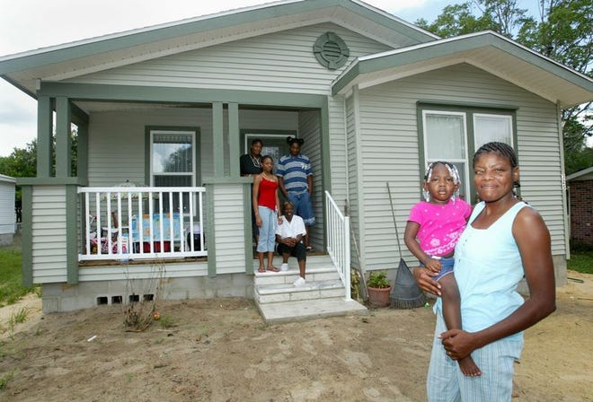 Willie Mae Raggs holds granddaughter Alize Raggs while the rest of her family waits on the porch of their new home in Lake Wales, which was provided by Palm Harbor Homes.