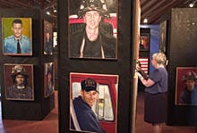 Museum director Joan Frederici places names on the paintings of firefighters killed in the 9/11 attacks. The 58-painting exhibit, which has toured the nation for two years, makes its final stop at the New England Fire and History Museum in Brewster until Sept. 12.