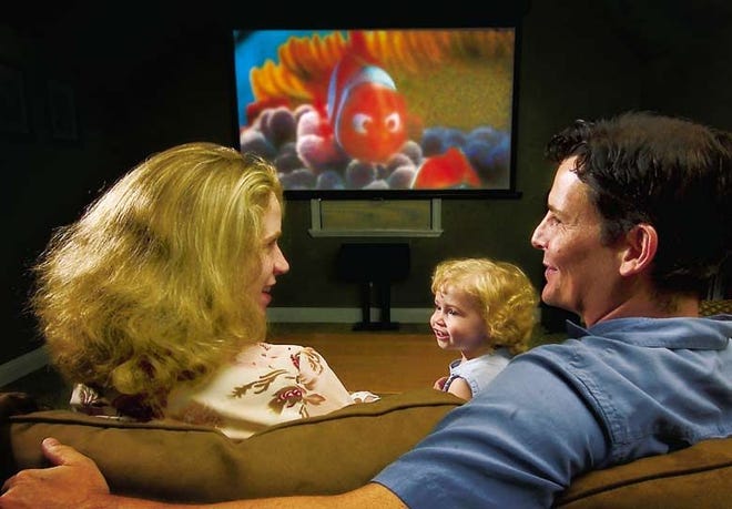 THE LEPINE FAMILY, FROM LEFT, MARCI, ISABELLE AND JEFF, ENJOY A MOVIE ON THEIR HOME THEATER SYSTEM.