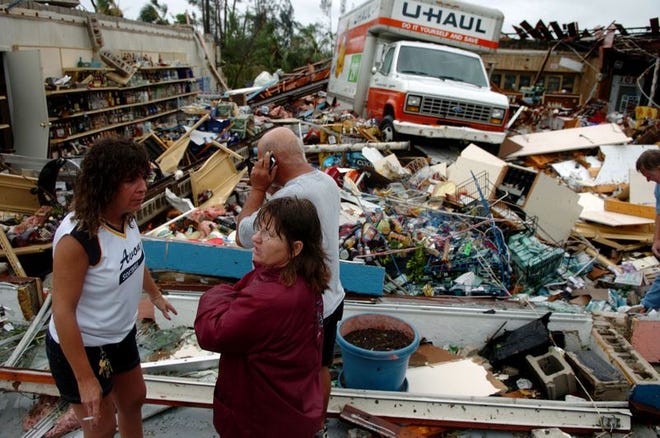 Employees of Beachcomber Liquors in Port Charlotte look at the damage caused by Hurricane Charley as it hit land Friday, August 13, 2004. A UHAUL truck sits in the middle of the store.