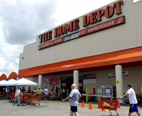People wait in line, left, to enter the Home Depot store in Orlando on Monday. The store's sign was damaged by hurricane Charley that hit the area Friday.