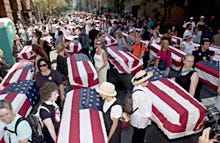 Volunteers with the group 1,000 Coffins hold fake coffins draped with flags, representing American men and women killed in Iraq, before the start of yesterday's protest march in New York City.