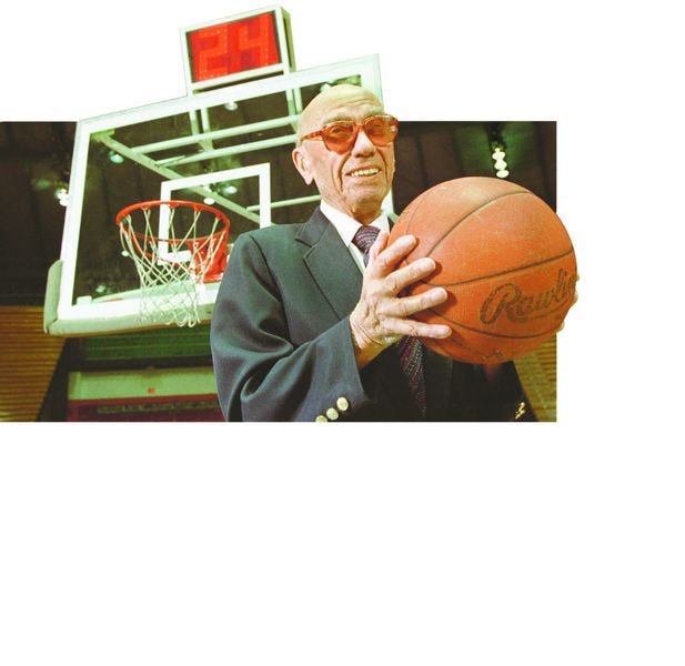 The late Danny Biasone, inventor of the 24-second clock for professional basketball, stands in front of a modern shot clock.