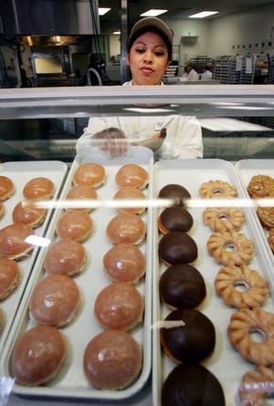 Mirtha Ortiz restocks a display case with glazed doughnuts at the Krispy Kreme store in Burbank, Calif., on Monday.
