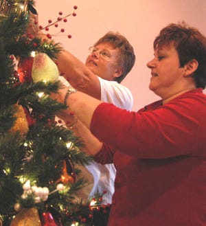 Chris Obney, right, interior design specialist for On Top of the World-Central, gets a helping hand from OTOW resident Sylvia Keller as she puts the finishing touches on "Season's Harvest" for the annual Festival of Trees.