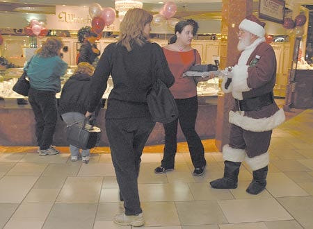 Santa Claus mingles with shoppers at Fox Run Mall in Newington on Friday morning. A number of entrepreneurs are trying to get some attention and break into the holiday market, including a Barrington woman who promotes mismatched socks and a Rollinsford man who represents a company that makes foldable surfboards to save traveling surfers the extra cost of shipping a regular board.