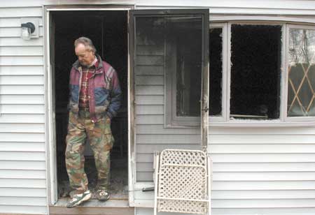 Warren Taylor steps outside from his home on West Shore Road in Raymond after inspecting the damage. A fire began Monday morning from a wood stove.