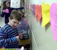 North Falmouth Elementary School student Mathew Abell helps post paper hearts that students have made to help children injured in the tsunami. A cash donation gives each student a heart on which they can write a personal message.