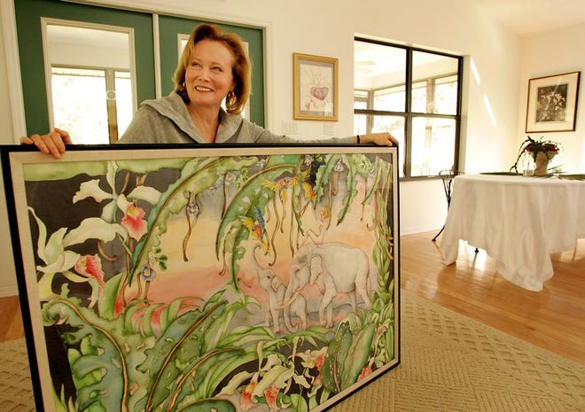 Artist Aline Kazokas holds her original watercolor painting titled "Her Dream" at her home in rural Gilchrist County. Kazokas painted this piece during her travels in Thailand. She said the woman in the painting is herself riding the back of Thailand, represented as white elephants.