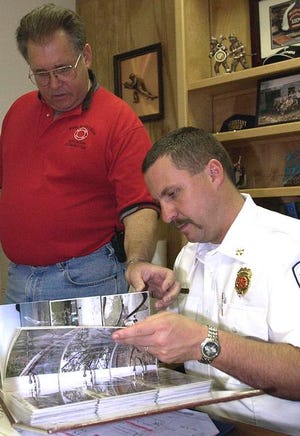 Fire and Rescue Advisory Committee member David Johnson, left, shows some photographs of his trip to the Los Tables Fire Department in Panama to Tim Garren, battalion chief at Valley Hill Fire and Rescue on Tuesday afternoon.