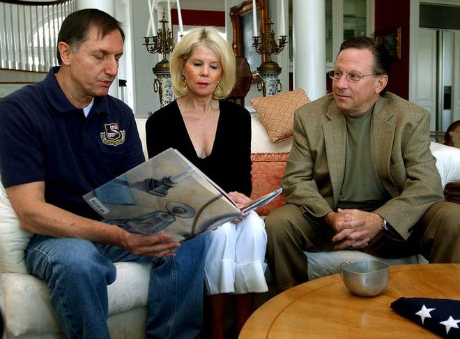 Vietnam veteran and former prisoner of war Tom Hanton, left, looks at the book "America's White Table" at the Charleston home of its author, Margot Theis Raven, center, along with

fellow veteran and POW Chuck Jackson.